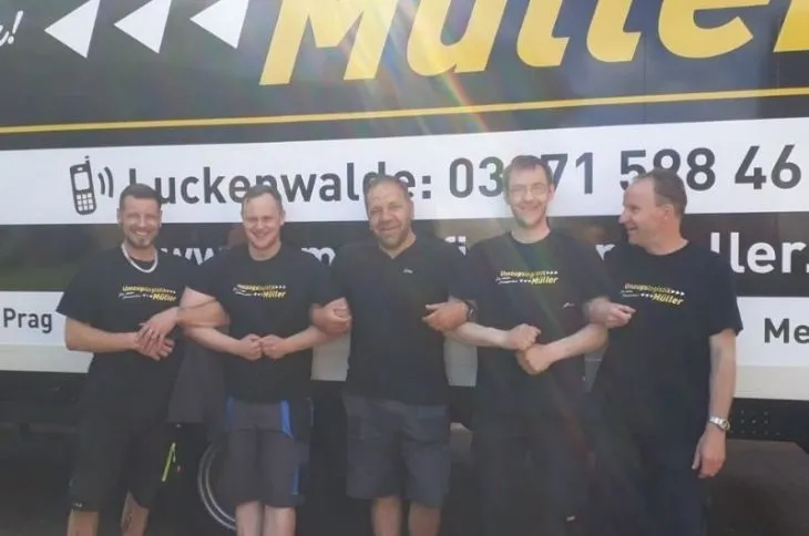 umzugsteam gruppiert sich vor umzugswagen